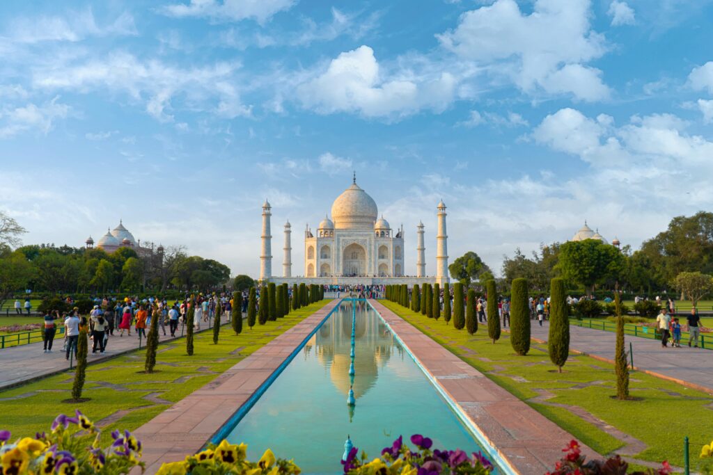 A beautiful view of the Taj Mahal in Agra, India, with clear blue skies and vibrant gardens.